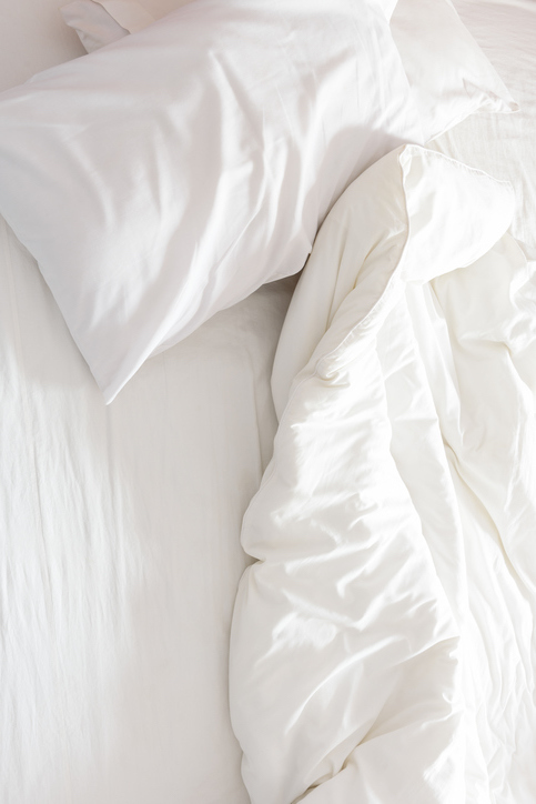 Top view of an unmade bed with crumpled bed sheet.